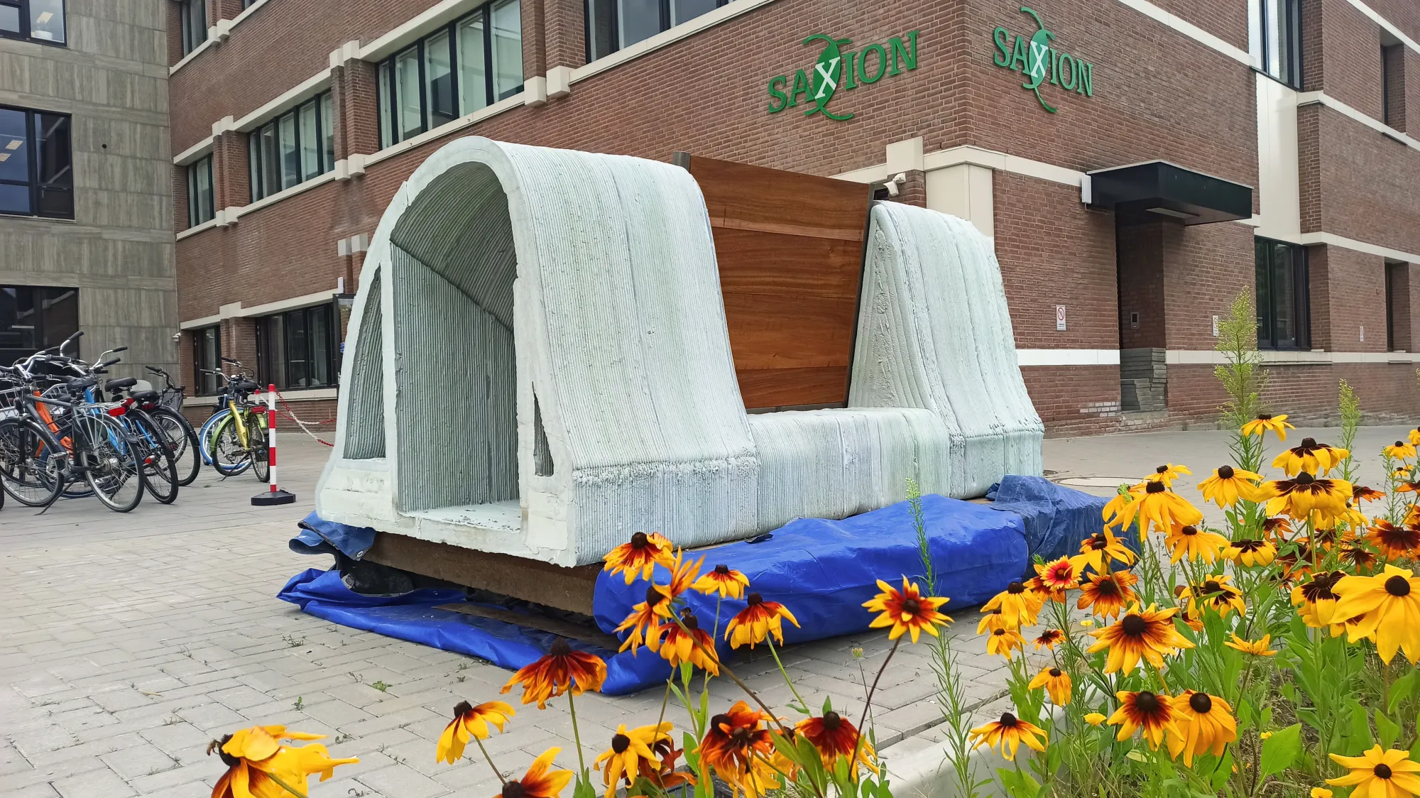 Assembled dam prototype displayed beside flowers on the Saxion campus