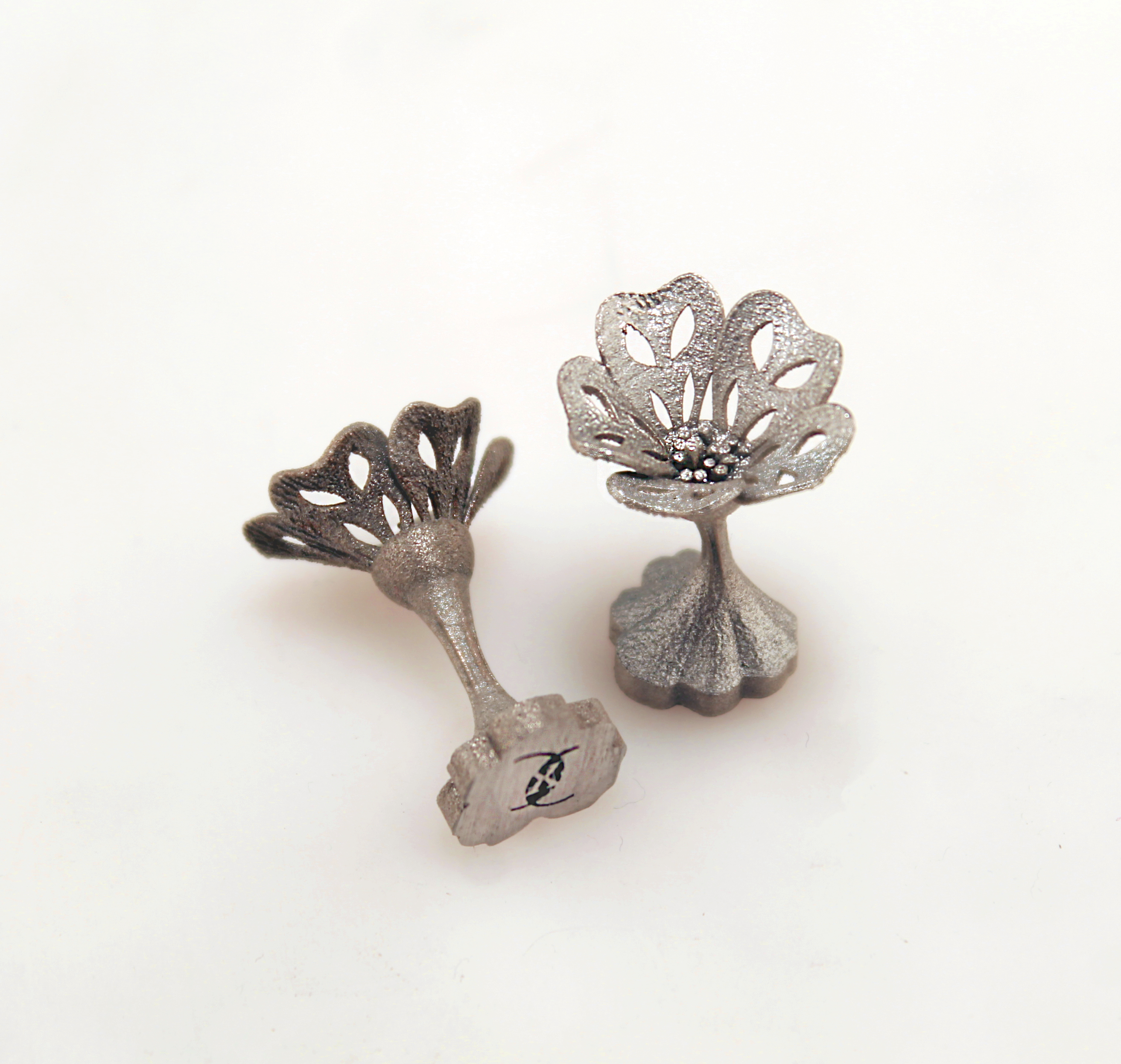 Two open-flower cufflinks, with one turned to reveal its stem and engraved reverse