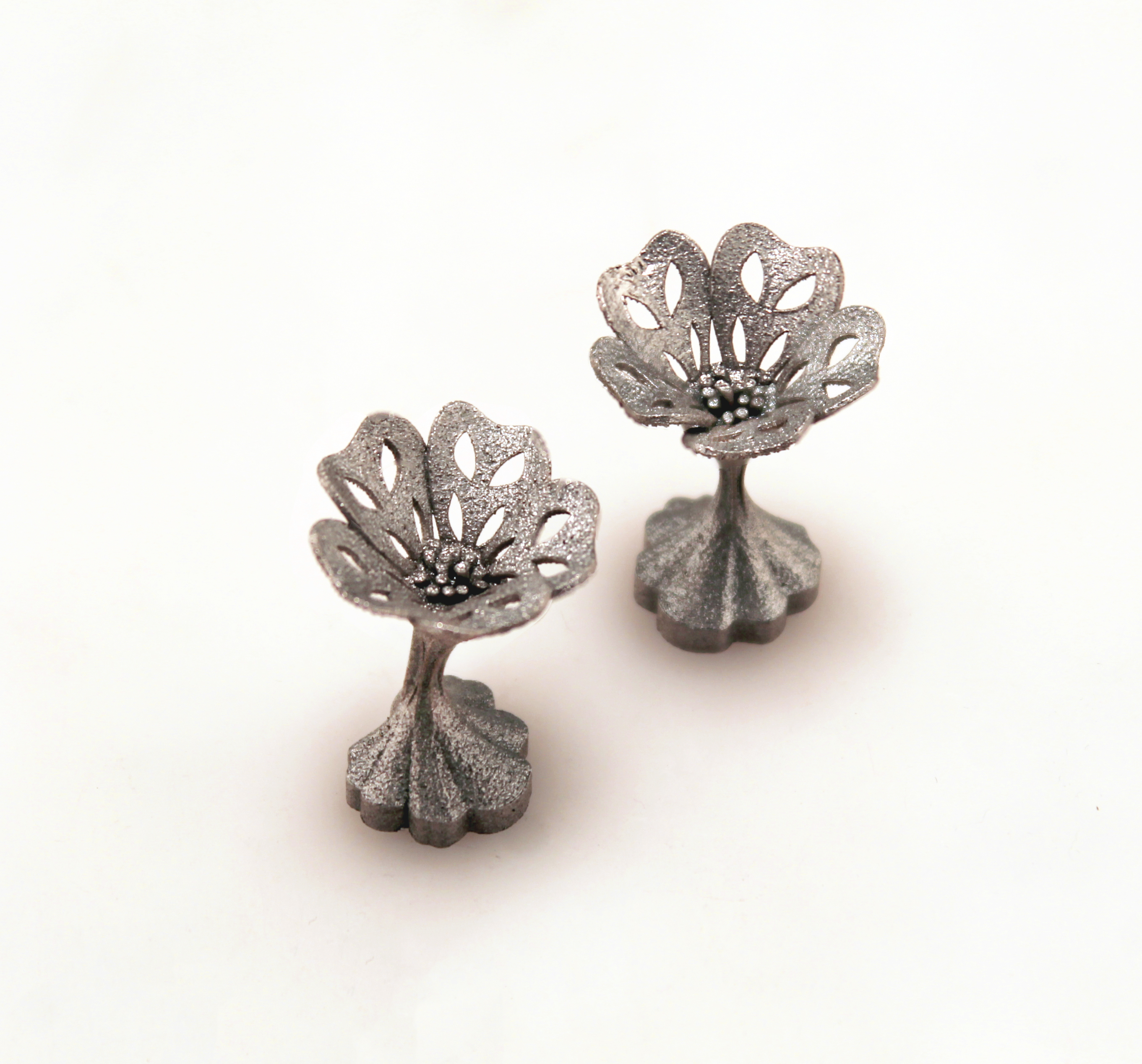 A finished pair of open-flower cufflinks standing upright