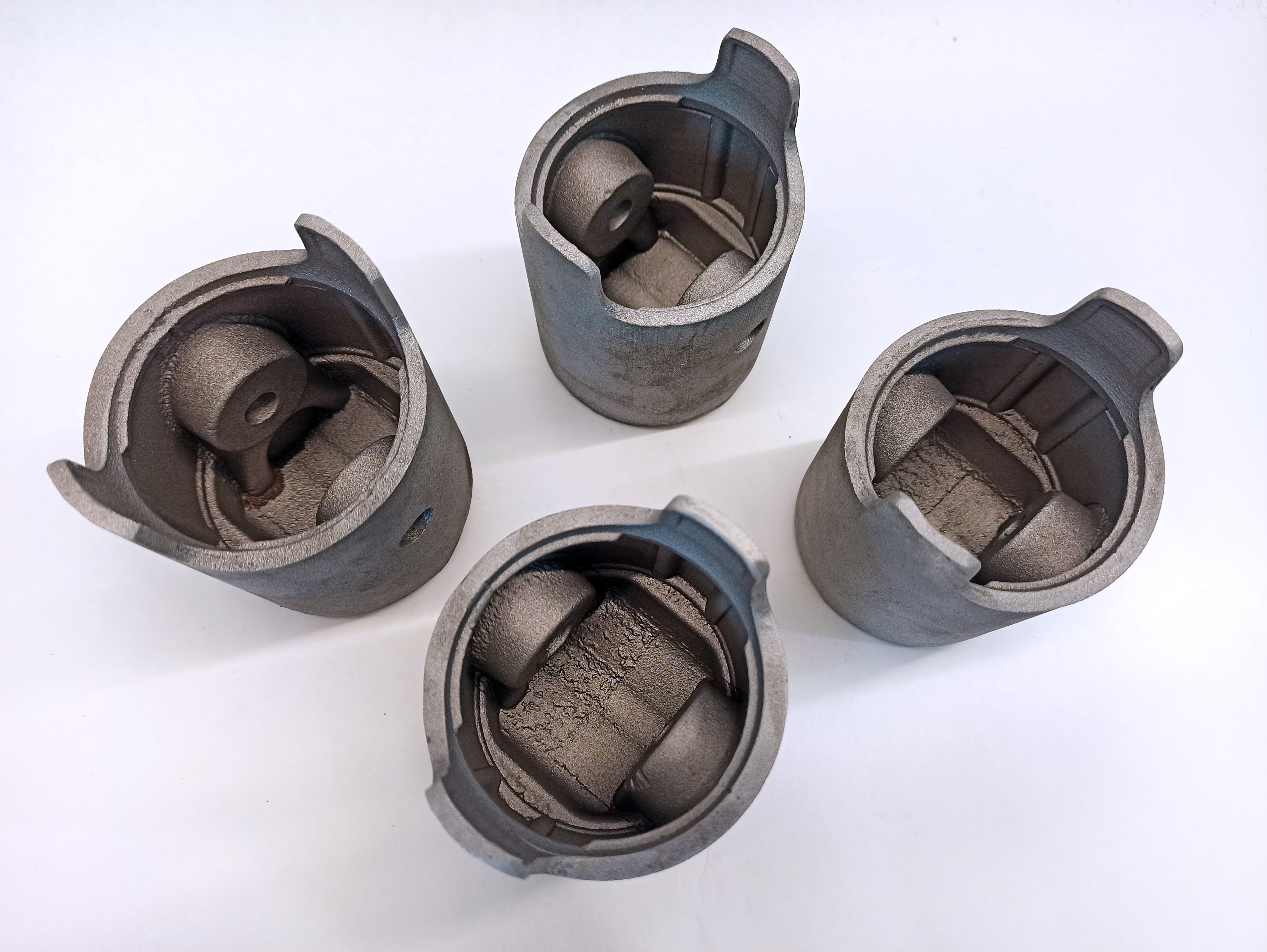 Four cast pistons viewed from beneath to show their internal cavities and pin bosses