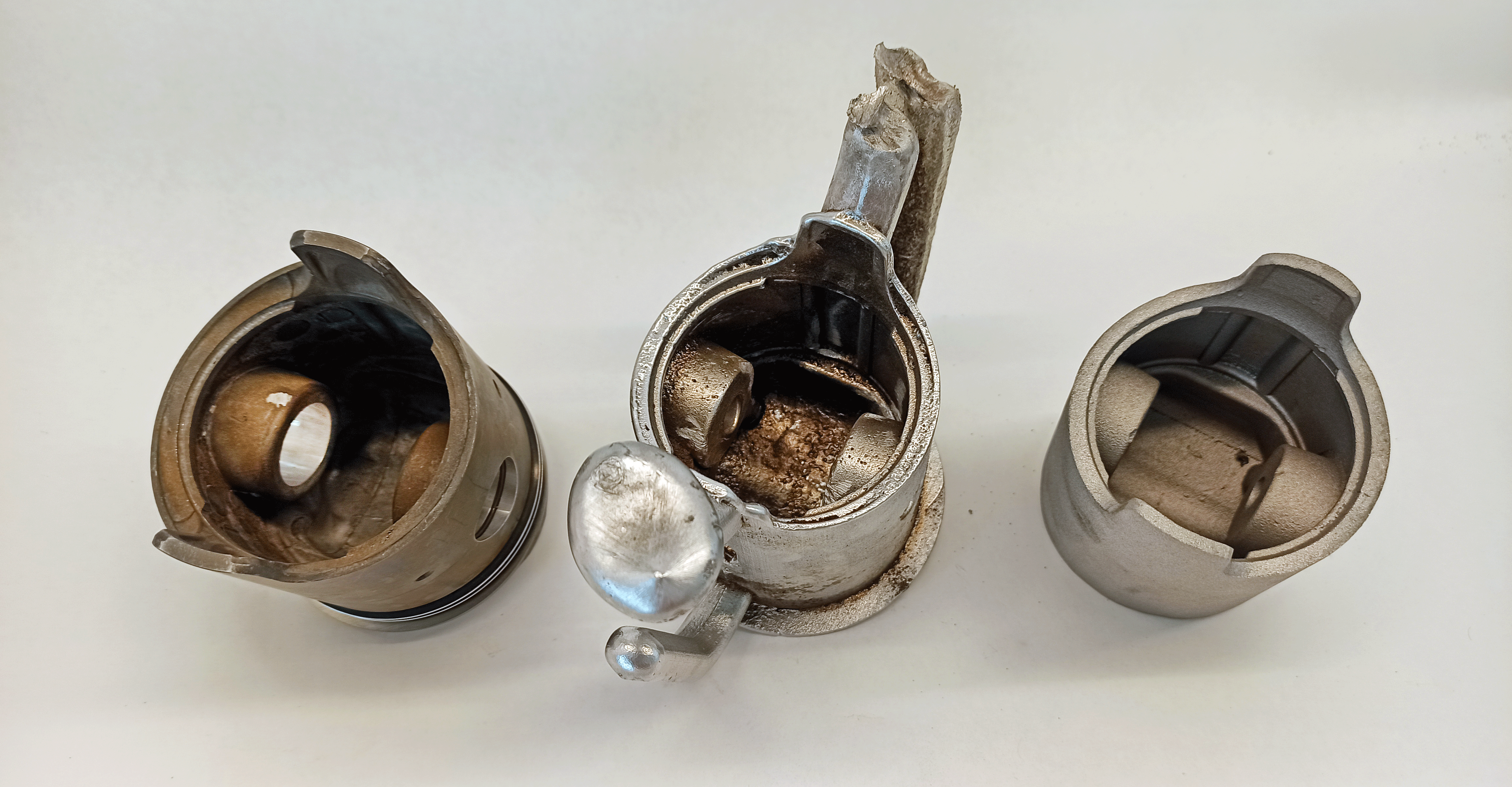 Underside comparison of an original piston, a casting with runners, and a trimmed casting