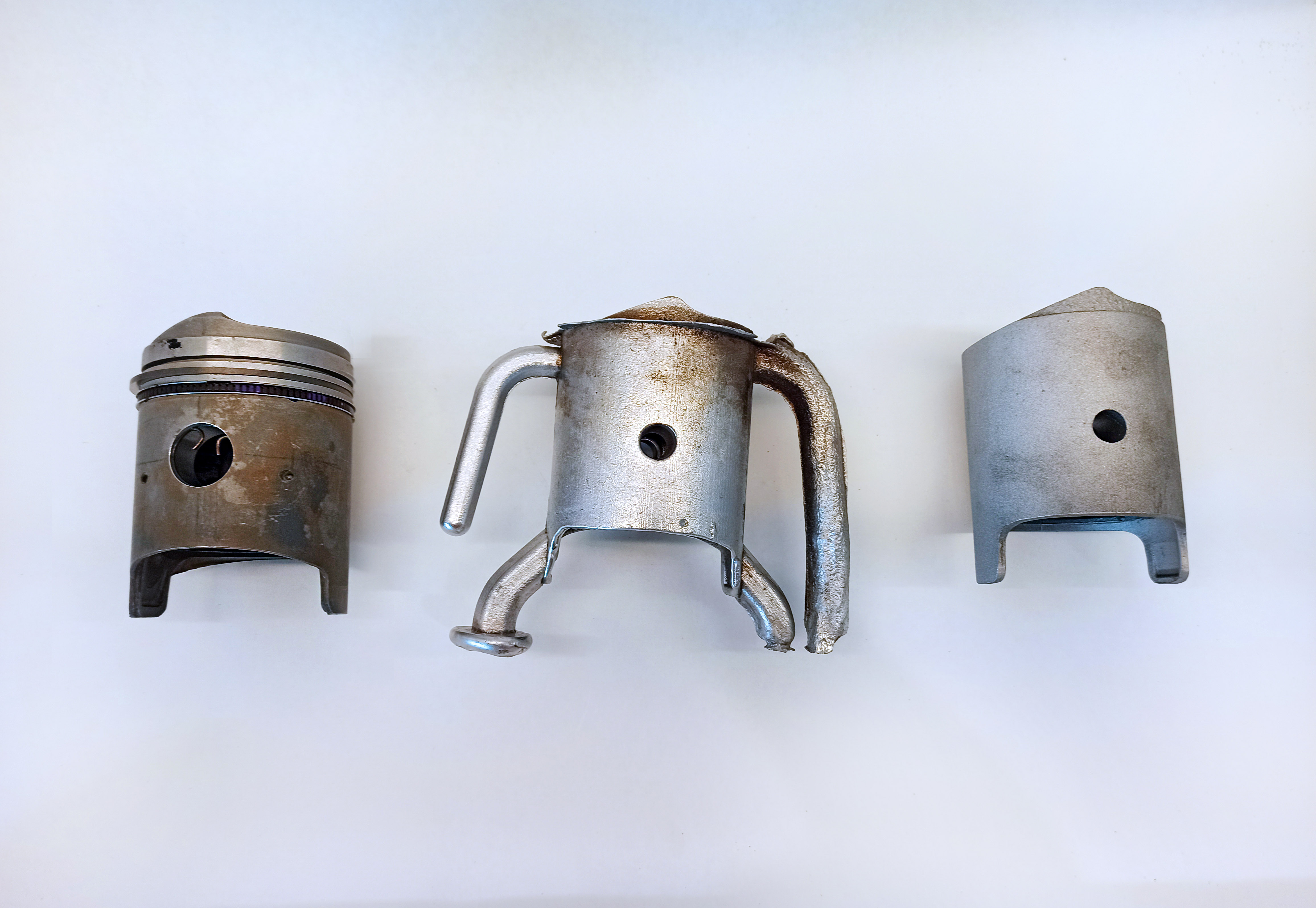Original piston beside a fresh casting with runners and a trimmed casting