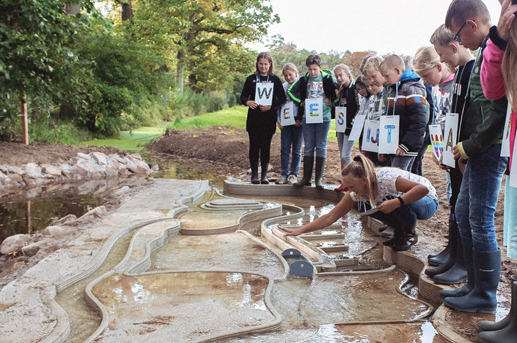 Primary school students gathered around the model during a water-management demonstration